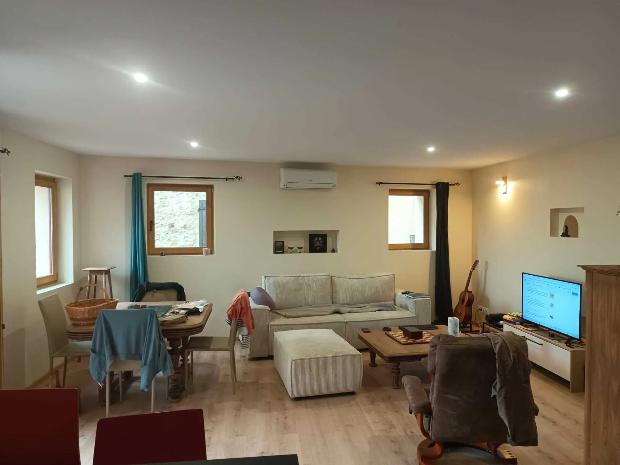Salon rénové avec murs et plafond lisses, éclairage encastré et mobilier chaleureux.