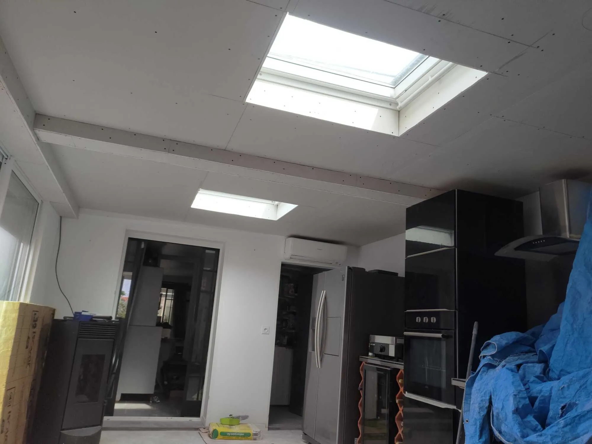 Plafond en plaques de plâtre avec fenêtres de toit dans une cuisine en rénovation.